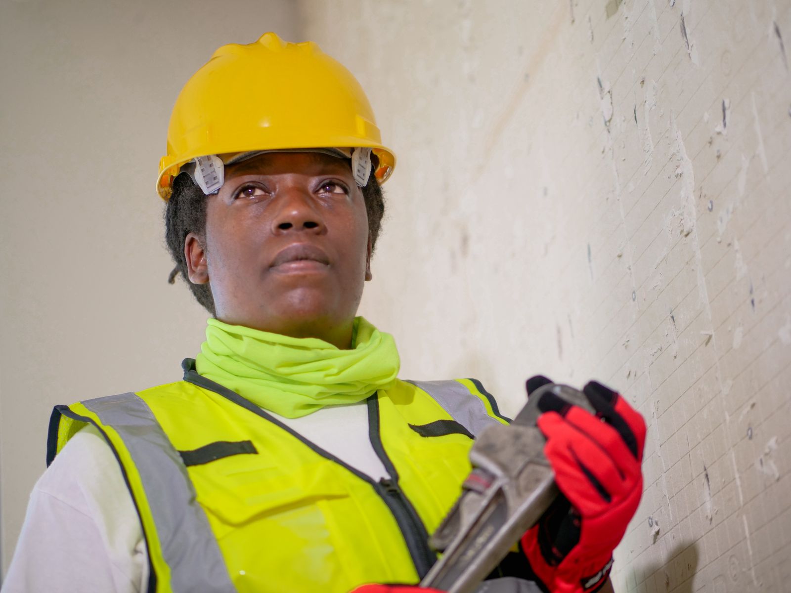 Black woman plumbing professional holding a pipe wrench and wearing protective equipment